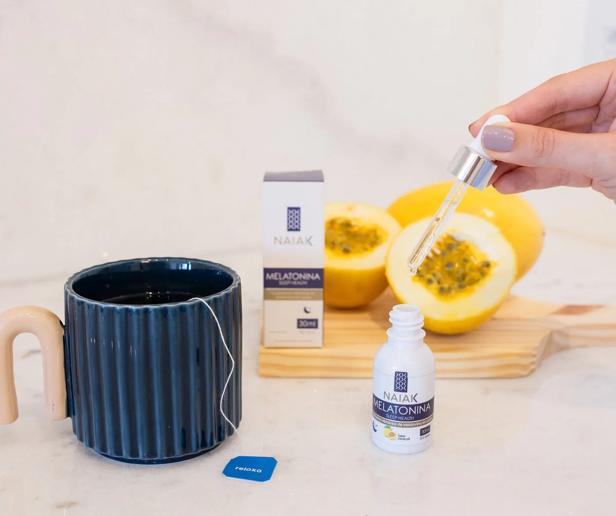 Melatonina em gotas Naiak sabor maracujá ao lado de uma caneca e maracujás