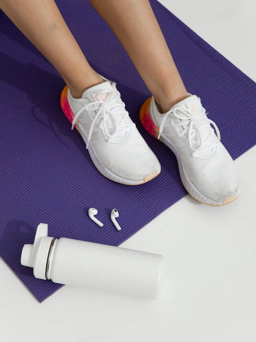 Tênis sobre tapete de treino com garrafa de água