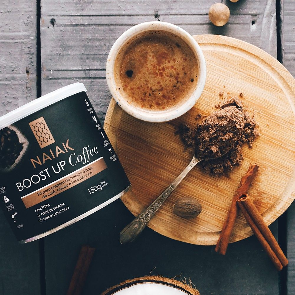 Lata de Boost Up Coffee ao lado de uma xícara de café e de uma colher com o pó