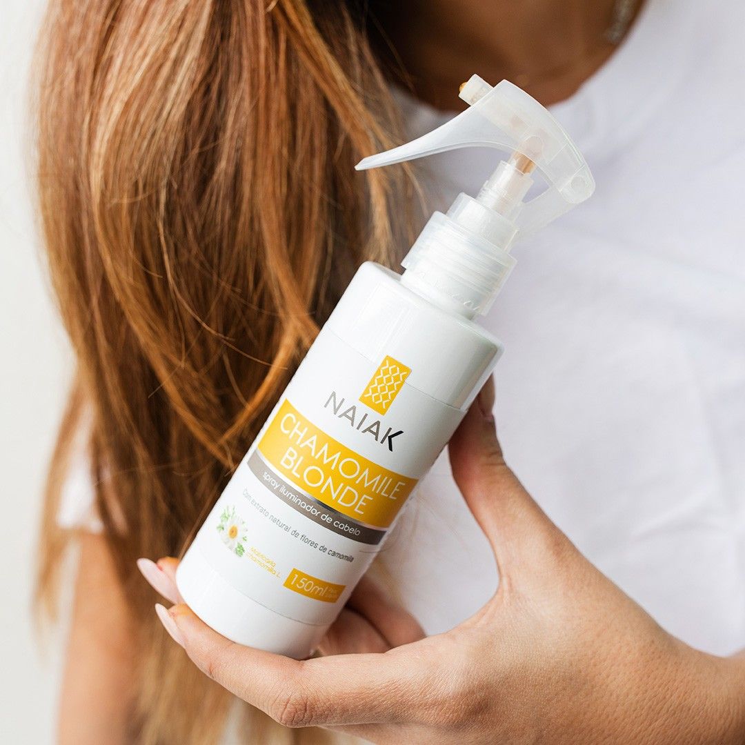 Chamomile Blonde Naiak: mão segurando o spray junto a cabelos loiros