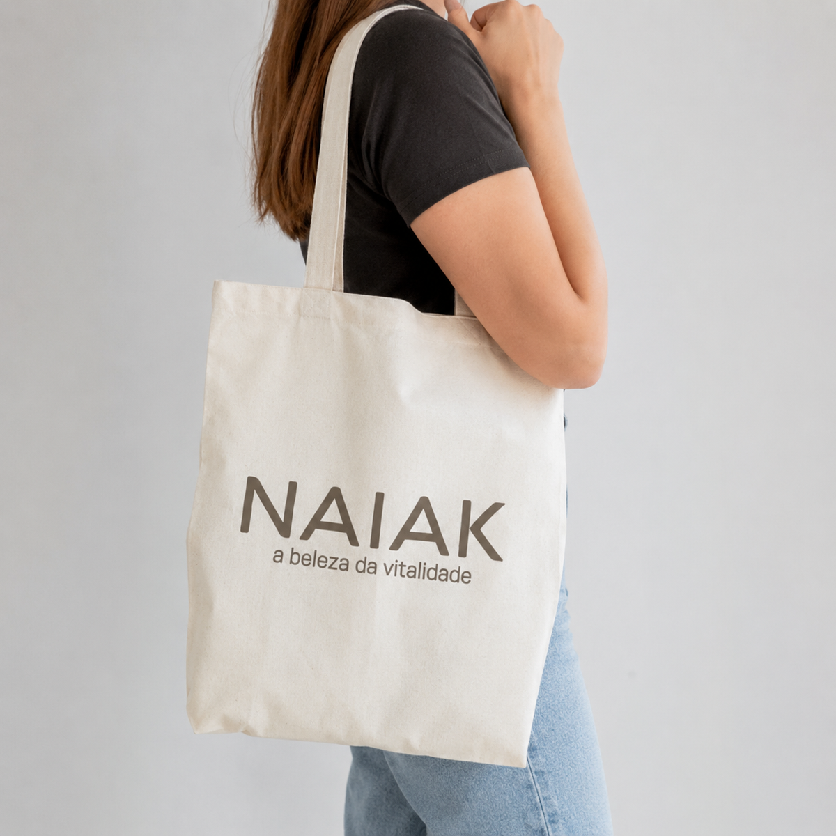 Ecobag 100% Algodão Naiak com a frase a beleza da vitalidade, no ombro de uma mulher