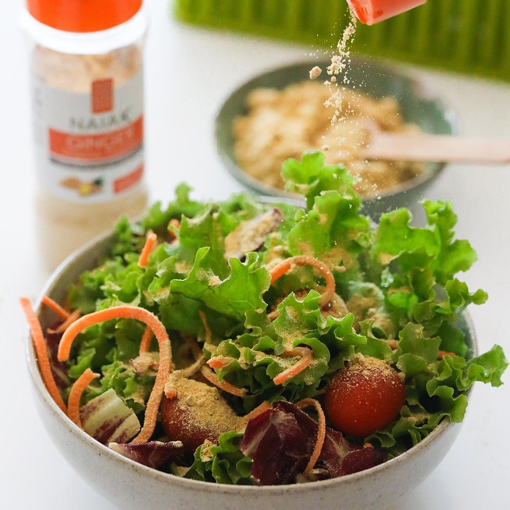 Gengibre em Pó Orgânico Naiak: gengibre em pó sendo polvilhado sobre uma salada