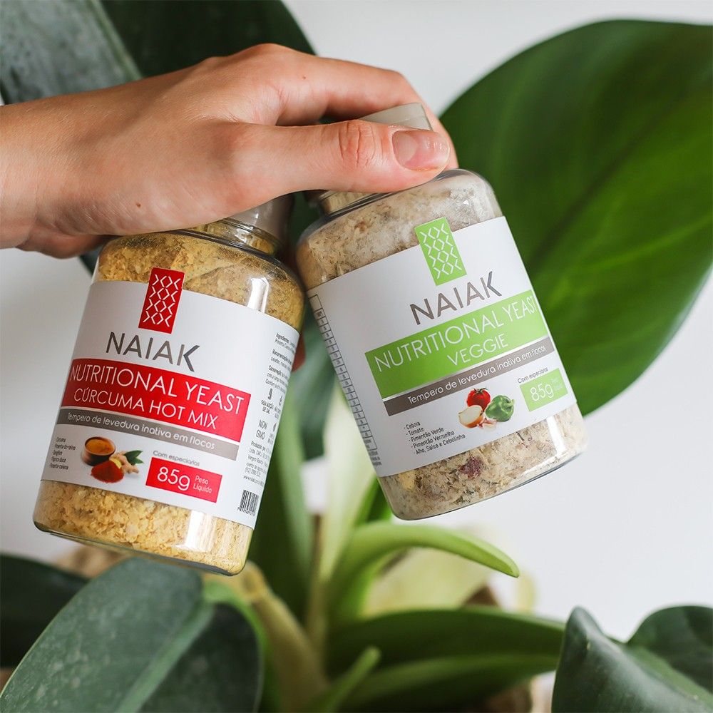 Nutritional Yeast Naiak: mão segurando os potes Cúrcuma Hot Mix e Veggie