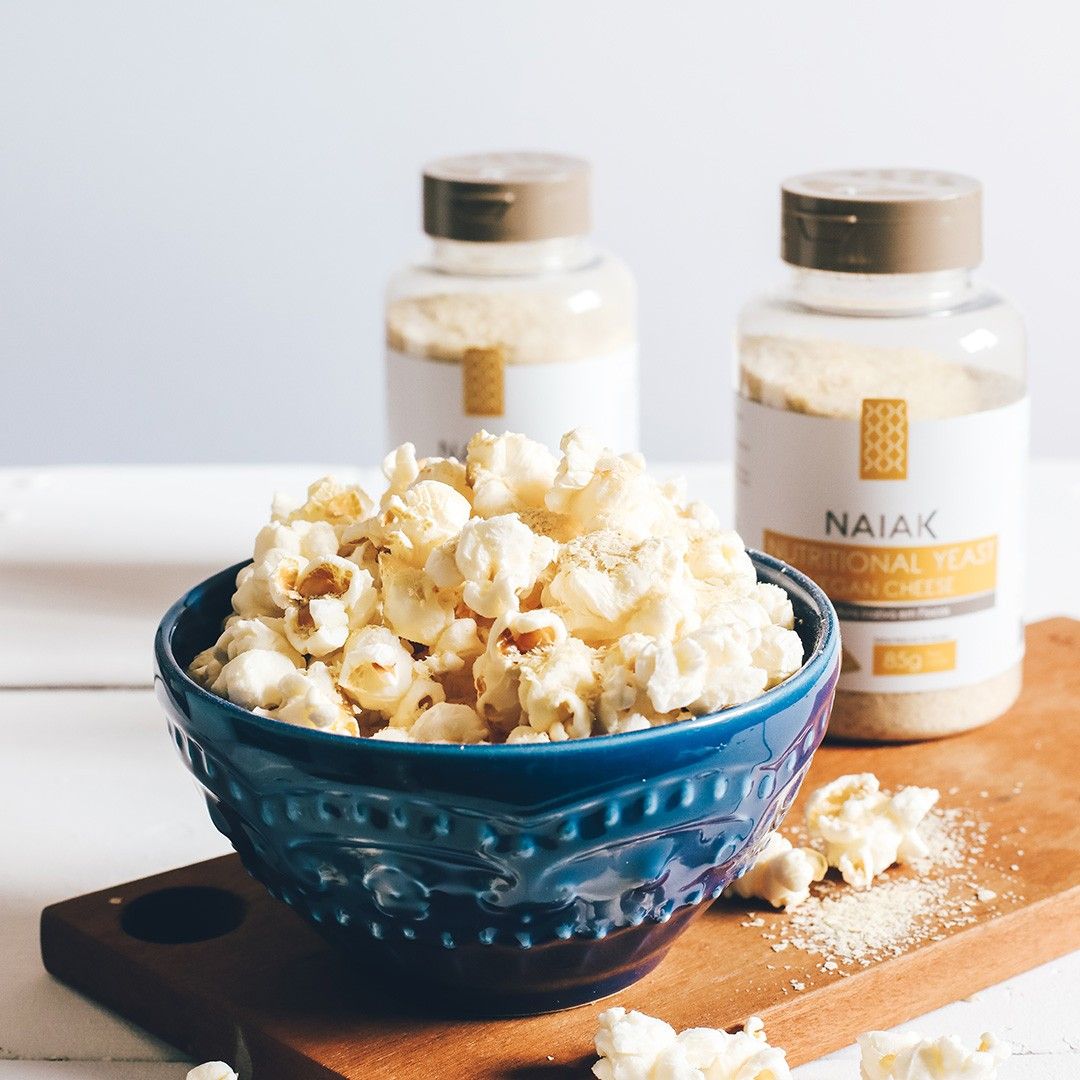 Nutritional Yeast Vegan Cheese Naiak: tigela de pipoca com dois potes ao fundo